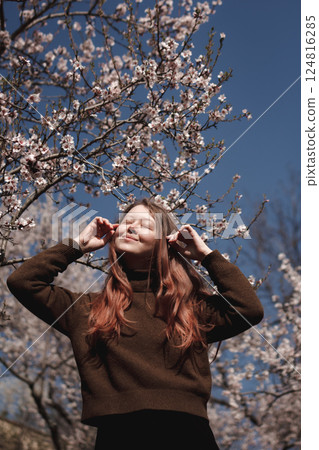 Young woman enjoying spring blossom almond tree in prague, petrin gardens 124816285