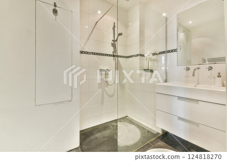Stylish bathroom featuring a glass shower enclosure, sleek modern fixtures, and elegant white tiles, creating a clean and contemporary aesthetic. Stylish bathroom featuring a glass shower enclosure, sleek modern fixtures, and elegant white tiles, creating a clean and contemporary aesthetic. 124818270