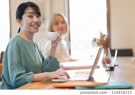 A young woman working in a cafe while drinking coffee A young woman working in a cafe while drinking coffee 124818315