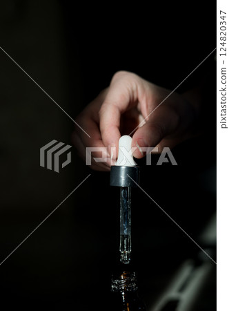 Hand holds pipette with serum 124820347