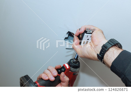 Electrician is using drill to install an electrical outlet with USB ports in ceiling at home. Electrician is using drill to install an electrical outlet with USB ports in ceiling at home. 124820871