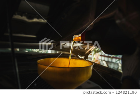 Mechanic pouring motor oil to engine with copy space on black background. Refueling and pouring oil quality into the engine motor car Transmission and Maintenance Gear. Energy fuel concept. 124821190