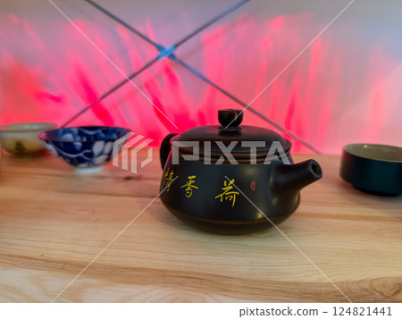 Clay teapot with golden calligraphy on wooden surface. Essence of traditional tea ceremony and the appreciation of Eastern cultural heritage Clay teapot with golden calligraphy on wooden surface. Essence of traditional tea ceremony and the appreciation of Eastern cultural heritage 124821441