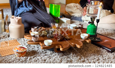 A woman pours yellow tea during a traditional gongfu tea ceremony on a carved wooden tray. Ritual, attention and mindfulness through tea preparation A woman pours yellow tea during a traditional gongfu tea ceremony on a carved wooden tray. Ritual, attention and mindfulness through tea preparation 124821485