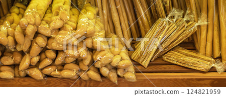Packed breadsticks and bread rolls arranged on wooden shelves inside local bakery. Colorful selection of bread products in bakery pastry shop Packed breadsticks and bread rolls arranged on wooden shelves inside local bakery. Colorful selection of bread products in bakery pastry shop 124821959