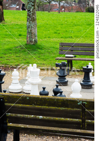Chess pieces await a strategic battle in a serene park, inviting players to engage in thoughtful competition under a clear sky during a tranquil afternoon Chess pieces await a strategic battle in a serene park, inviting players to engage in thoughtful competition under a clear sky during a tranquil afternoon 124822046