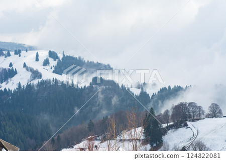 Winter serenity envelops picturesque mountain landscape during a cloudy day in the heart of nature, showcasing vast snow-covered hills and evergreen trees Winter serenity envelops picturesque mountain landscape during a cloudy day in the heart of nature, showcasing vast snow-covered hills and evergreen trees 124822081