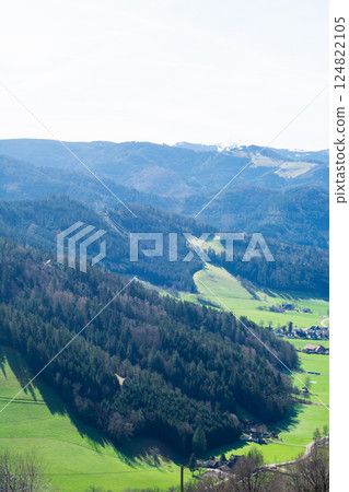 Enchanting landscape revealing rolling hills and dense forest under a clear blue sky in a tranquil rural area Enchanting landscape revealing rolling hills and dense forest under a clear blue sky in a tranquil rural area 124822105