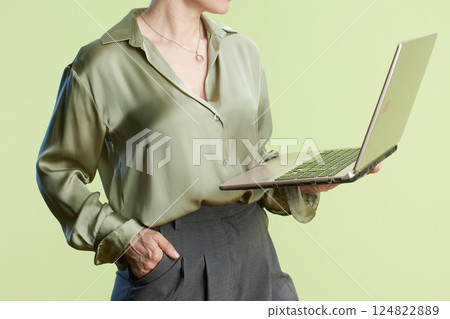 Professional woman with laptop on green background 124822889