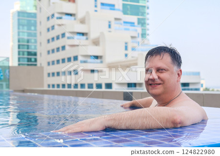 Relaxing by the pool, adult man swimming in clean cool water on a hot day 124822980