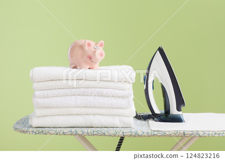 Piggy bank and iron on clean towels symbolizing household savings Piggy bank and iron on clean towels symbolizing household savings 124823216