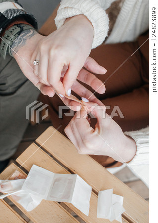 Close-up of a woman's hands applying a medical plaster to an injured finger during first aid. Accident and help from loved ones Close-up of a woman's hands applying a medical plaster to an injured finger during first aid. Accident and help from loved ones 124823899