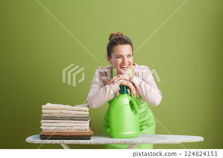 Content woman with laundry detergent on ironing board Content woman with laundry detergent on ironing board 124824151