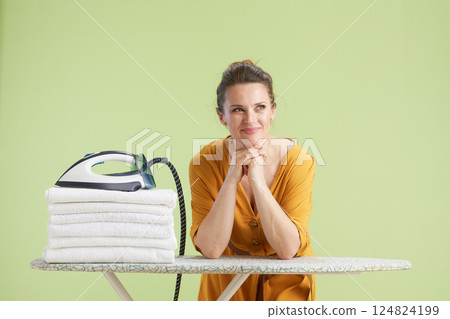 Woman resting by laundry pile with thoughtful look Woman resting by laundry pile with thoughtful look 124824199
