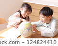 Elementary school boys and girls studying while looking at a globe 124824410