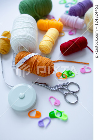 Colorful yarn and knitting supplies with measuring tape and scissors on white background Colorful yarn and knitting supplies with measuring tape and scissors on white background 124824453