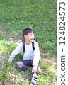 A boy sitting and laughing with a school bag on his back 124824573