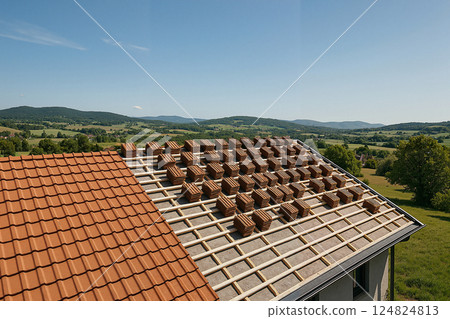 Construction of a summer house roofing in a scenic countryside setting with mountains in the background 124824813