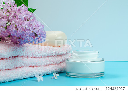 Spa and skin care concept. Towel, cream and soap on background of delicate lilac flowers. Spa and skin care concept. Towel, cream and soap on background of delicate lilac flowers. 124824927