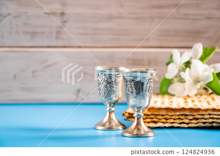 Happy passover. Metal goblet and traditional matzah on blue background. Symbols of Jewish holiday. Happy passover. Metal goblet and traditional matzah on blue background. Symbols of Jewish holiday. 124824936