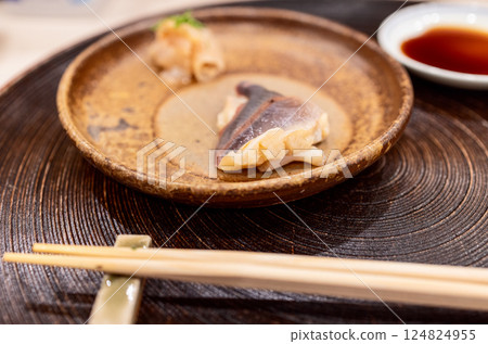 Surf clam sashimi presented on rustic ceramic plate with minimal garnish, captured with bokeh effect Surf clam sashimi presented on rustic ceramic plate with minimal garnish, captured with bokeh effect 124824955