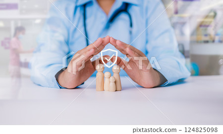 Doctor hand selects life insurance and investment to reduce risk, Wooden doll with shield means protection from disease and health insurance, Health care planning, Insurance and protection concept. Doctor hand selects life insurance and investment to reduce risk, Wooden doll with shield means protection from disease and health insurance, Health care planning, Insurance and protection concept. 124825098
