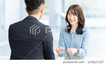 Two businessmen, male and female, exchanging business cards 124825107