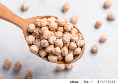 Organic chickpeas on wooden spoon on grey table background Organic chickpeas on wooden spoon on grey table background 124825155
