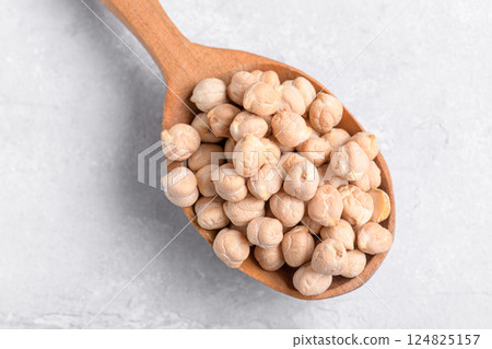 Dry chickpeas on wooden spoon on grey table background 124825157
