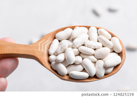 Navy beans on wooden spoon, close up 124825159