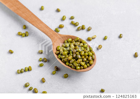 Mung beans in a wooden spoon on grey table background Mung beans in a wooden spoon on grey table background 124825163