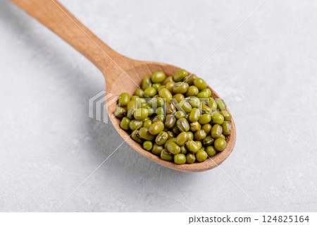 Healthy mung beans in a wooden spoon on grey table background Healthy mung beans in a wooden spoon on grey table background 124825164