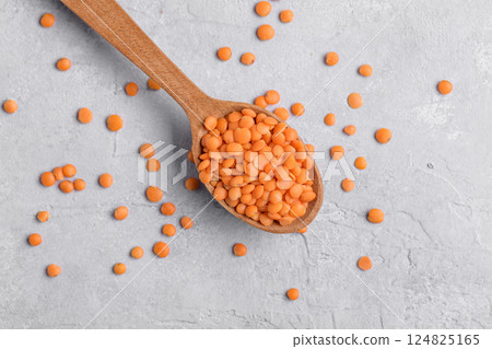 Organic red lentil on wooden spoon, close up Organic red lentil on wooden spoon, close up 124825165