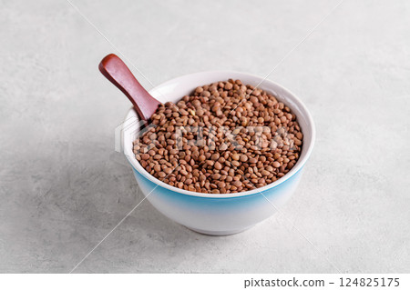 Raw lentils in ceramic bowl on grey background Raw lentils in ceramic bowl on grey background 124825175