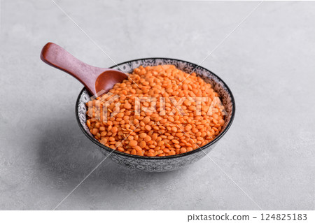 Dry red lentils in bowl with spoon on grey background Dry red lentils in bowl with spoon on grey background 124825183