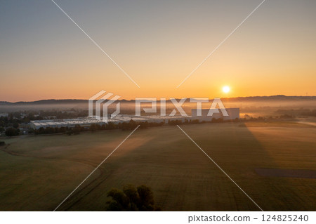 Drone shot at golden hour with a factory and agricultural fields 124825240