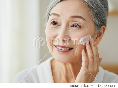 A senior woman applying skin care cream with a smile (AI-generated image) A senior woman applying skin care cream with a smile (AI-generated image) 124825483