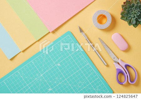 Paper art supplies: scissors, craft knife, eraser, tape, pastel colored paper. Place for your text. Scrapbooking work table 124825647