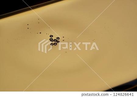 Texture of cosmetic oil on a gold background. Texture of cosmetic oil on a gold background. 124826641