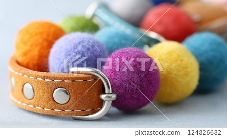 Colorful Felt Balls and Leather Strap Close Up on Soft Blue Background for Creative Crafts 124826682