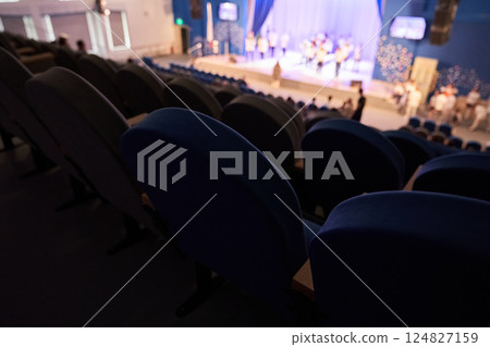 An empty theater hall. The rehearsal of the play. People in the auditorium are watching the performance. A music concert or festival. Out of focus. High quality photo 124827159
