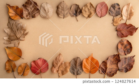 Warm seasonal frame with dry autumn leaves in earthy colors over textured paper, evoking rustic charm and natural comfort. 124827614
