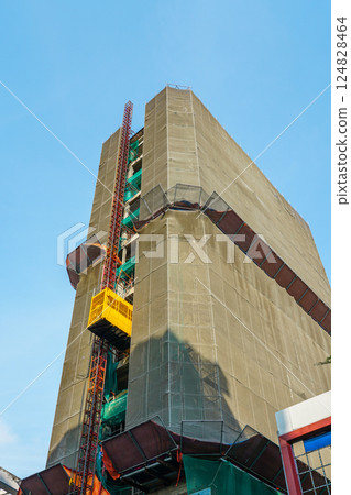 Renovation of a multi-story building, the building is surrounded by scaffolding and a safety net 124828464