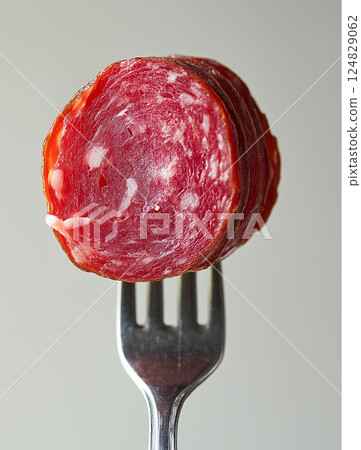 Delicious salami slices on a fork showcasing gourmet cuisine and deli meat for food lovers Delicious salami slices on a fork showcasing gourmet cuisine and deli meat for food lovers 124829062