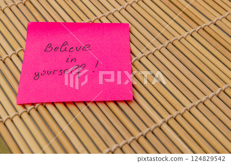 Positive affirmation note on pink sticky paper resting on bamboo mat Positive affirmation note on pink sticky paper resting on bamboo mat 124829542