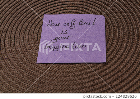 Inspirational message on a purple sticky note placed on textured surface 124829626