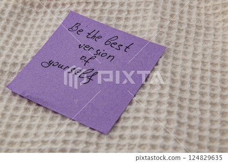 Encouraging note on a purple sticky reminder resting on fabric 124829635