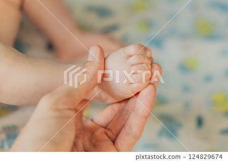 Father's hand gently holding his baby's tiny foot, symbolizing love, protection, and family bond. Parenthood, care, and tenderness concept 124829674