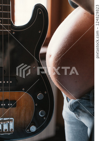 Pregnant Belly and Bass Guitar Side by Side Close-Up Pregnant Belly and Bass Guitar Side by Side Close-Up 124829823