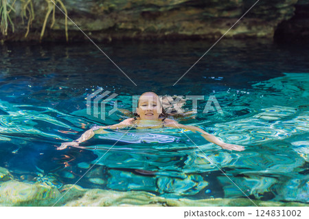 Female tourist enjoying a refreshing swim in a Mexican cenote with turquoise water. Adventure, travel, and nature exploration concept Female tourist enjoying a refreshing swim in a Mexican cenote with turquoise water. Adventure, travel, and nature exploration concept 124831002
